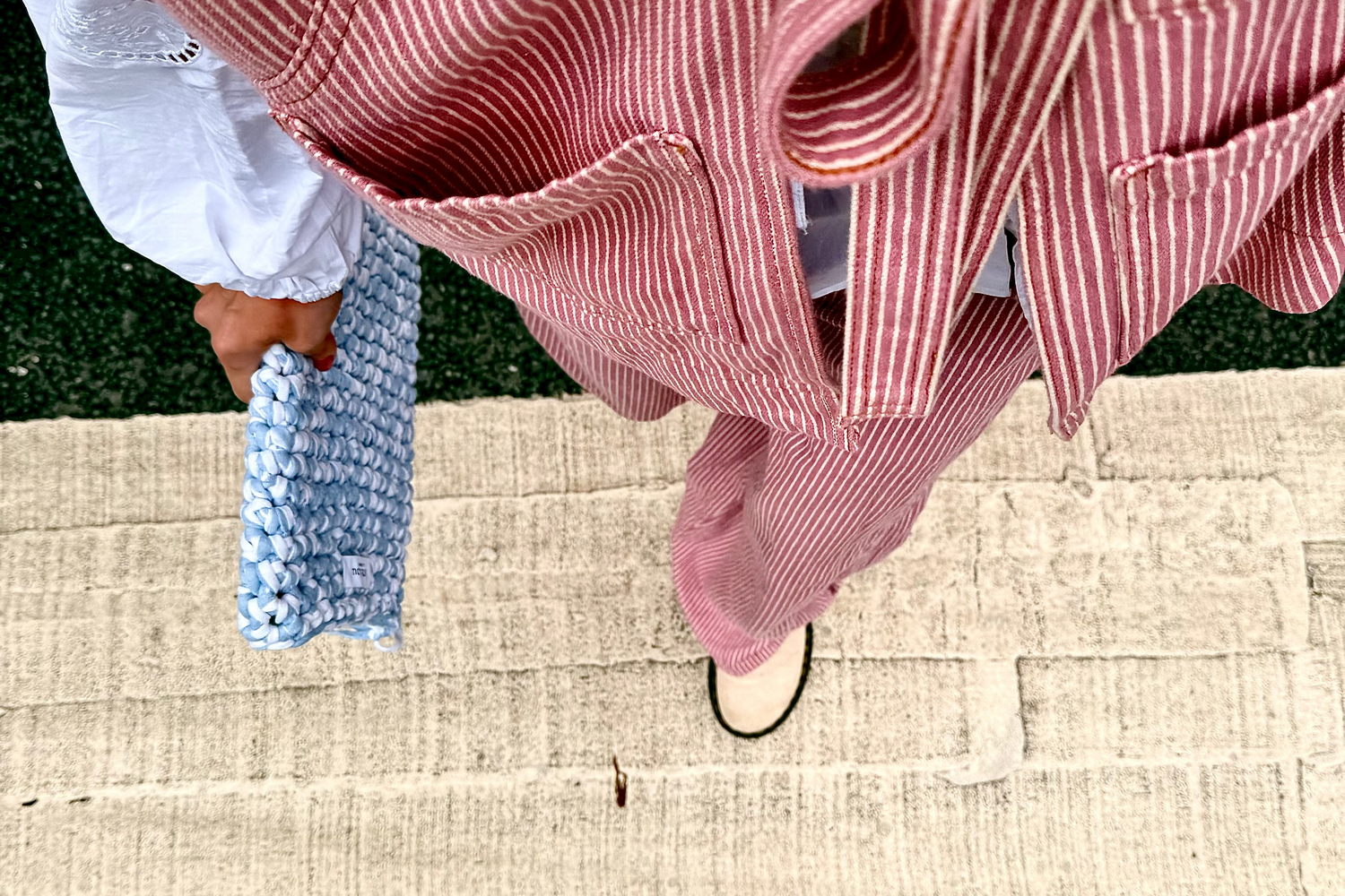 Person wearing pink and white striped trousers with a white lace top, standing on a beige step.